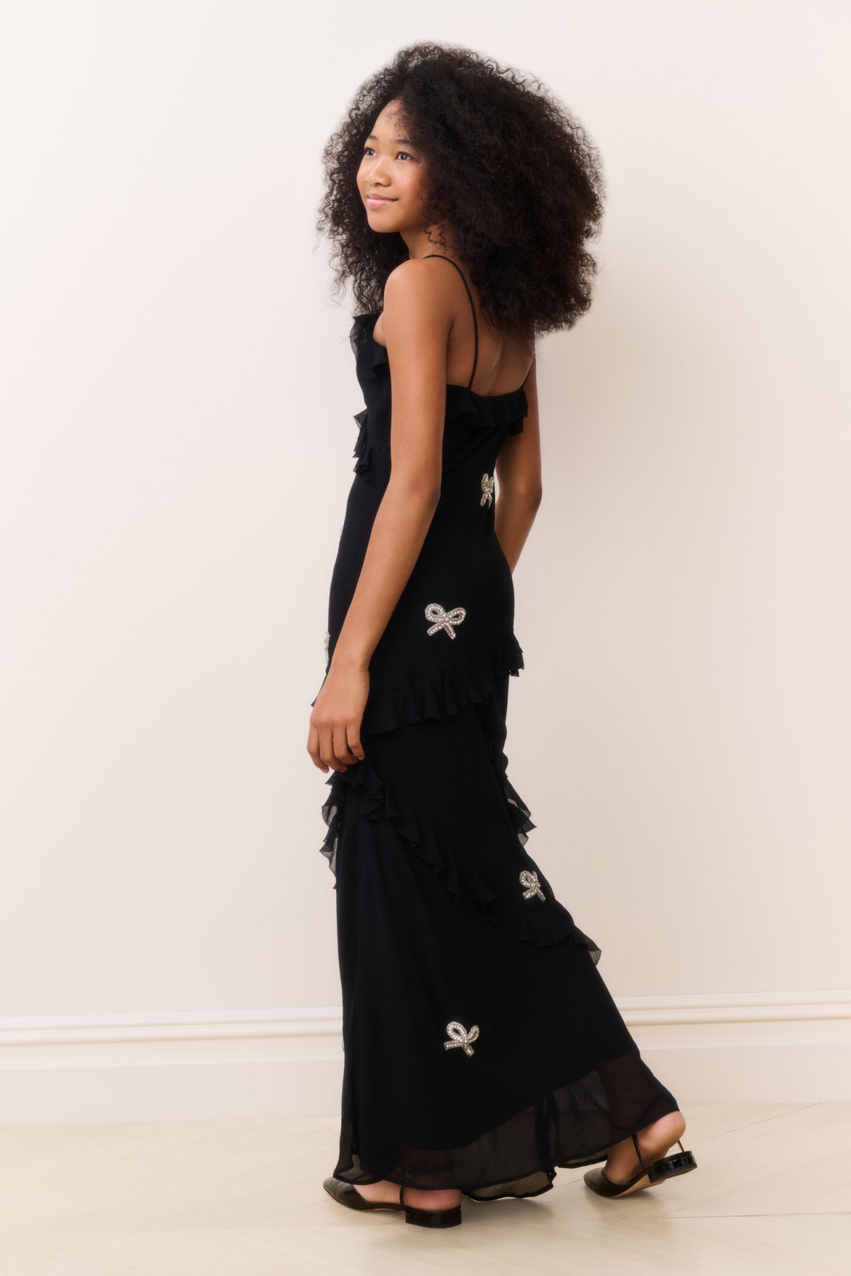 Black sleeveless mini dress with tiered ruffle skirt and bow appliques