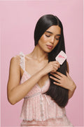 Pink floral mini detangling hair brush held in hand, white handle