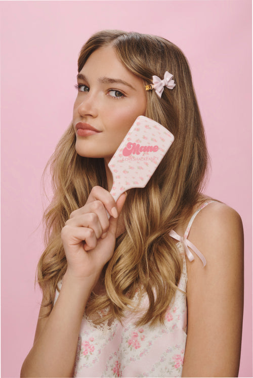 Pink floral mini detangling brush with logo text on white handle