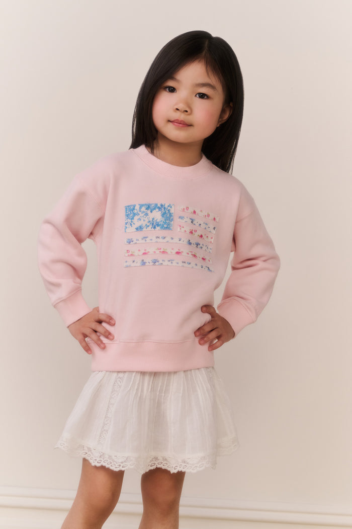 Girls' pink crewneck pullover with colorful front graphic, paired with lace skirt