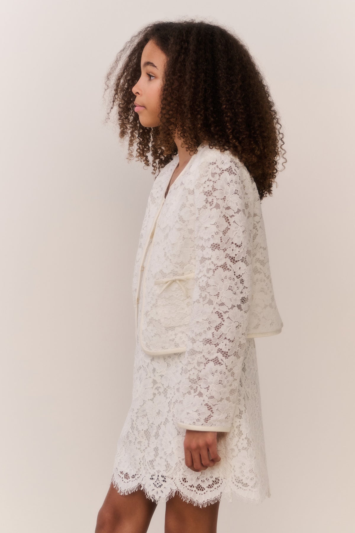 Ivory lace jacket with front button placket and long sleeves, side view