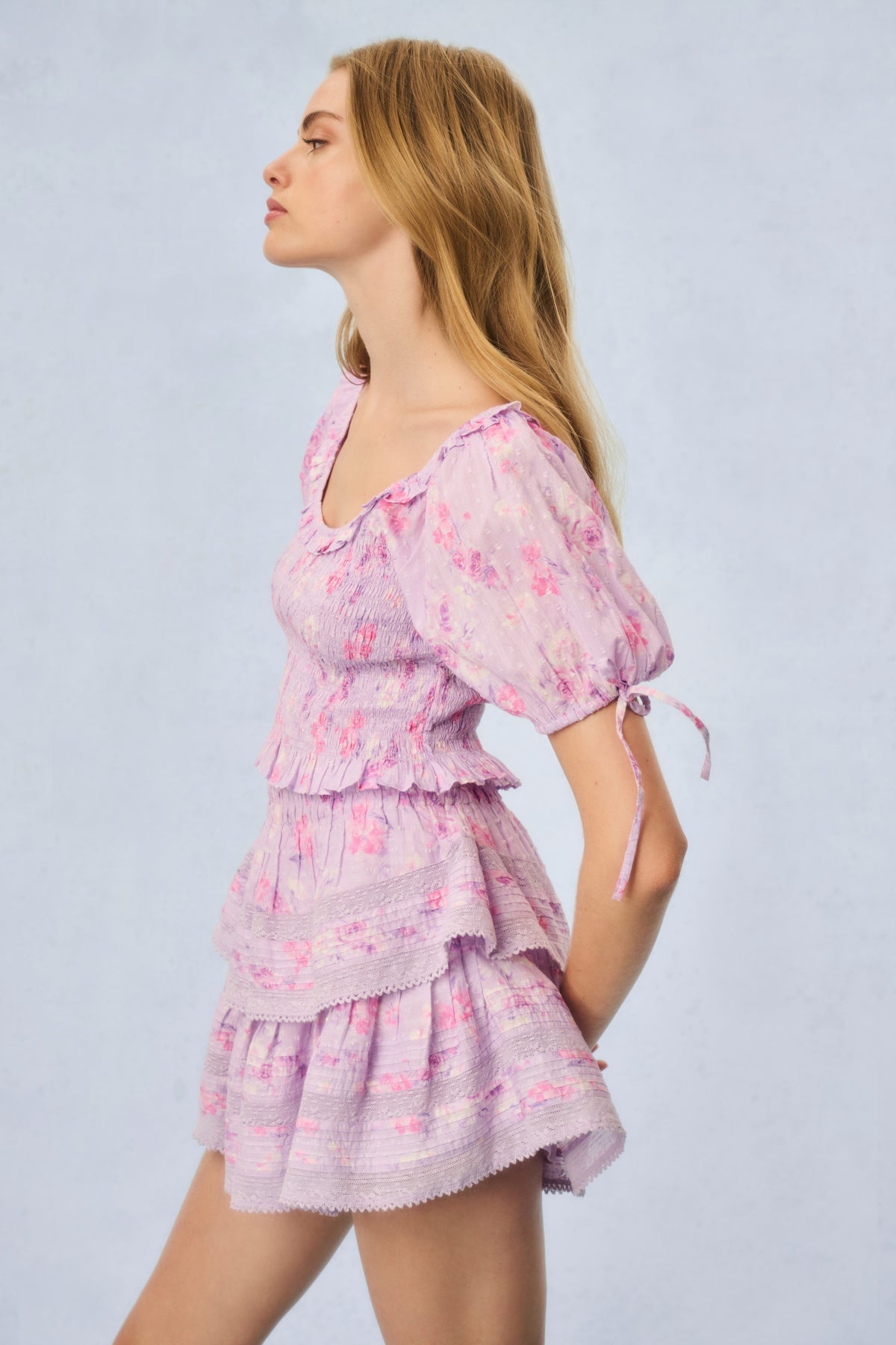 Pink printed peplum top, side view, puff sleeves with tie details and ruffled tiers
