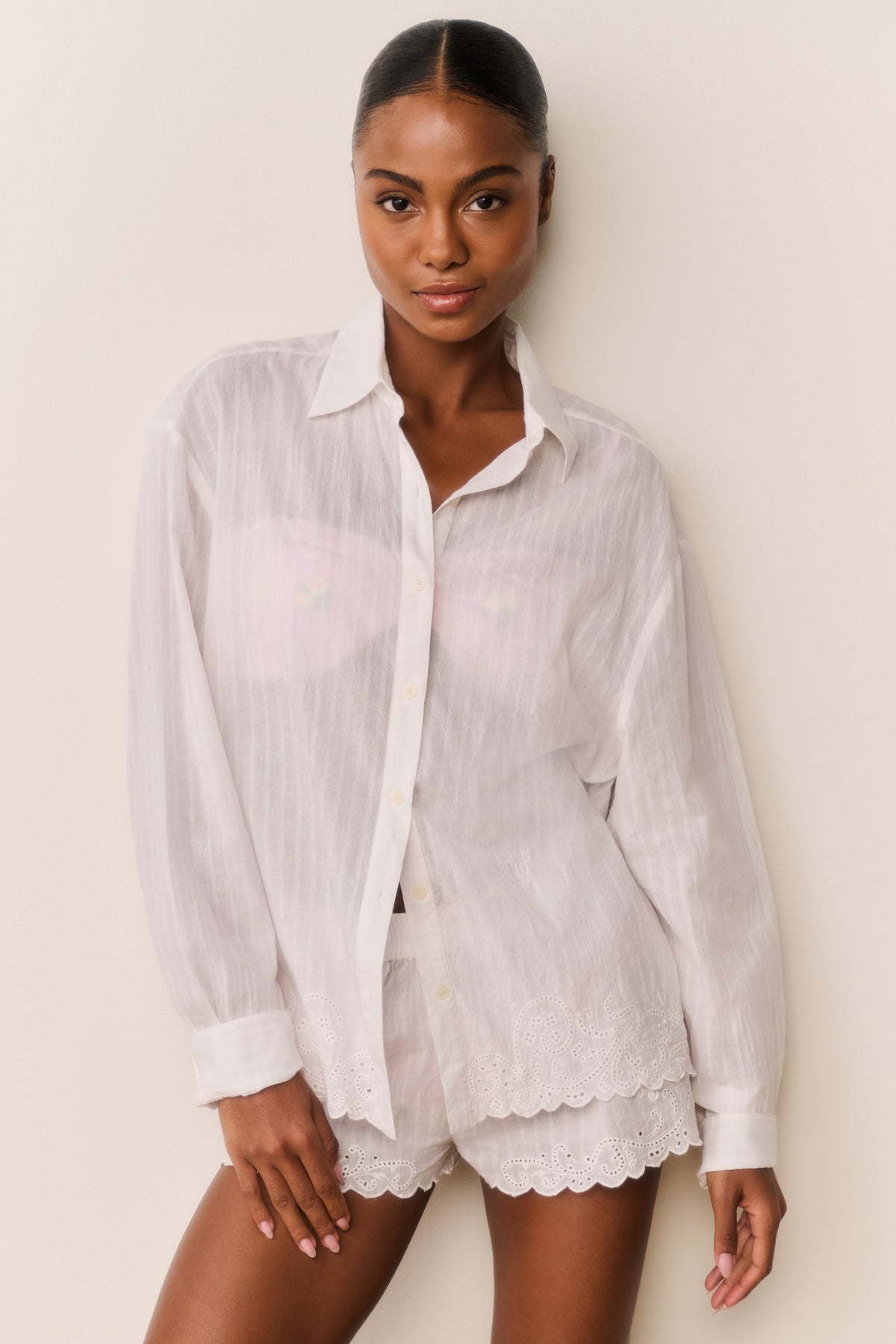 White embroidered cotton button-up shirt on model, long sleeves, scalloped hem and cuffs