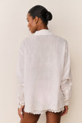Embroidered cotton button-up shirt from back view, long sleeves, white with scalloped hem