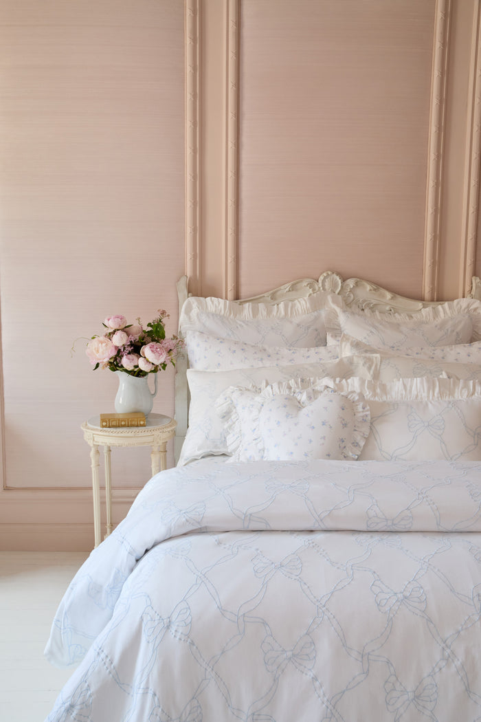 White embroidered duvet cover and shams with ruffled edging and layered decorative pillows