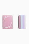 Two pastel mahjong tiles: pink face with lace border and striped side