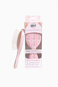 Mini detangling hair brush in pink floral, next to retail box