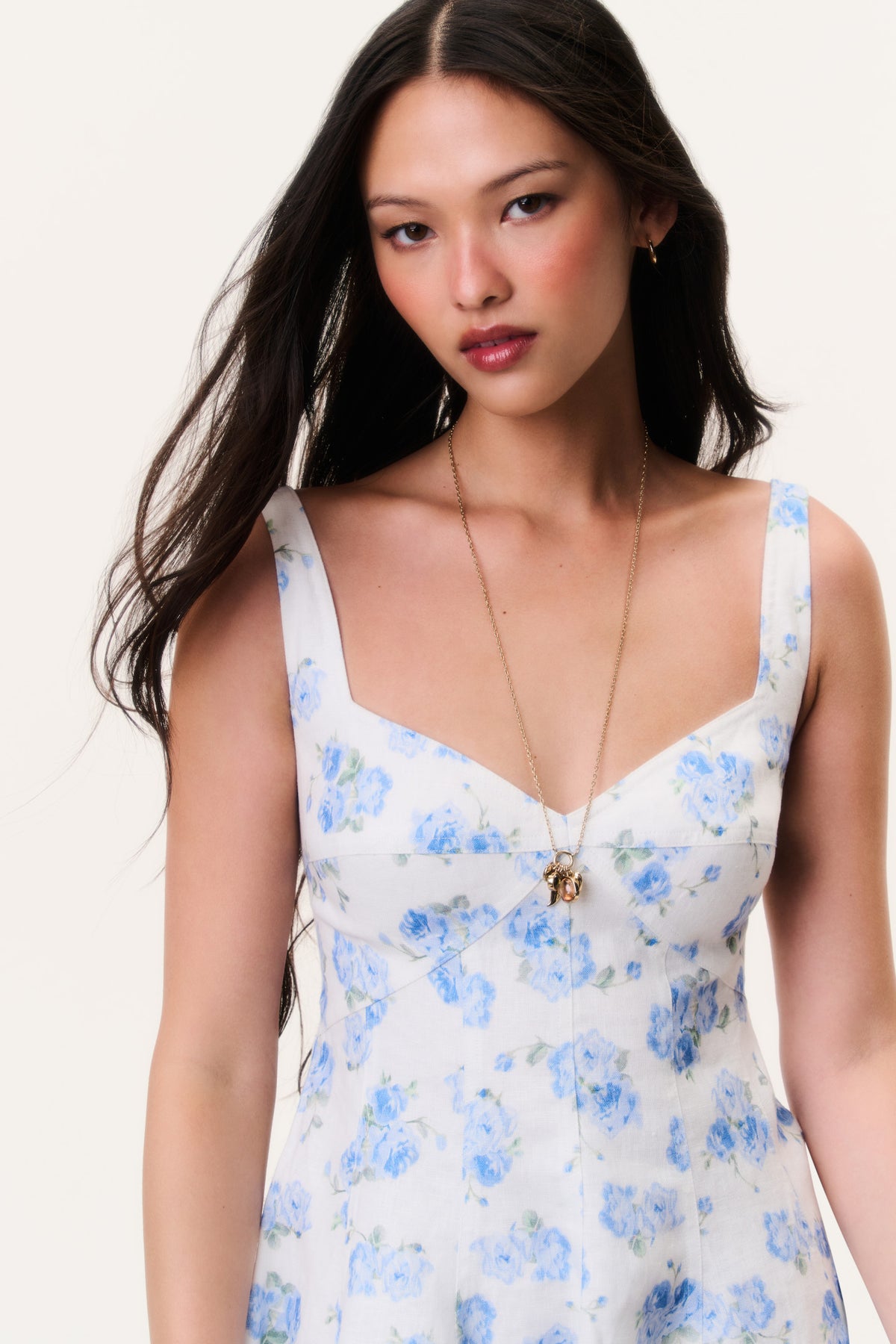 Blue floral linen mini dress with V-neck, thin straps, and decorative center detail