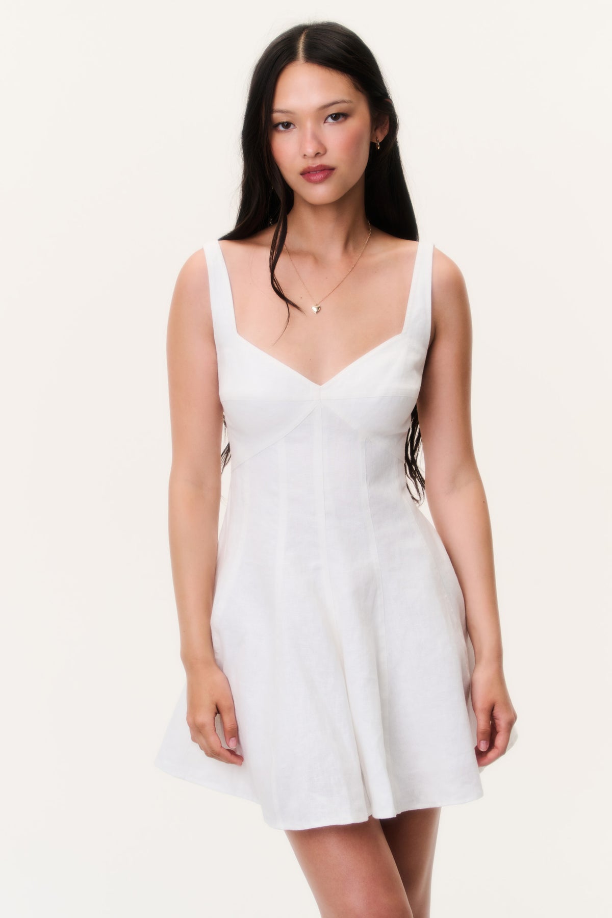 White linen mini dress with spaghetti straps, V neckline, and flared skirt
