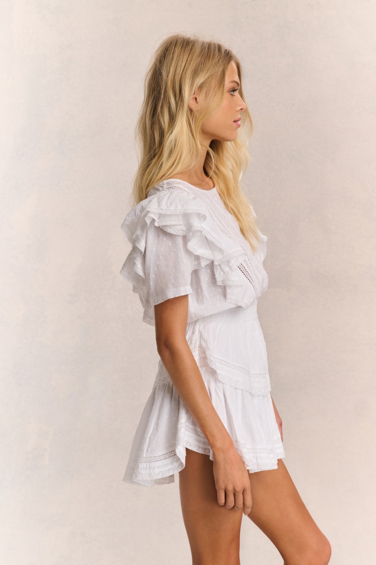 White mini dress side view with ruffled sleeves and tiered skirt layers