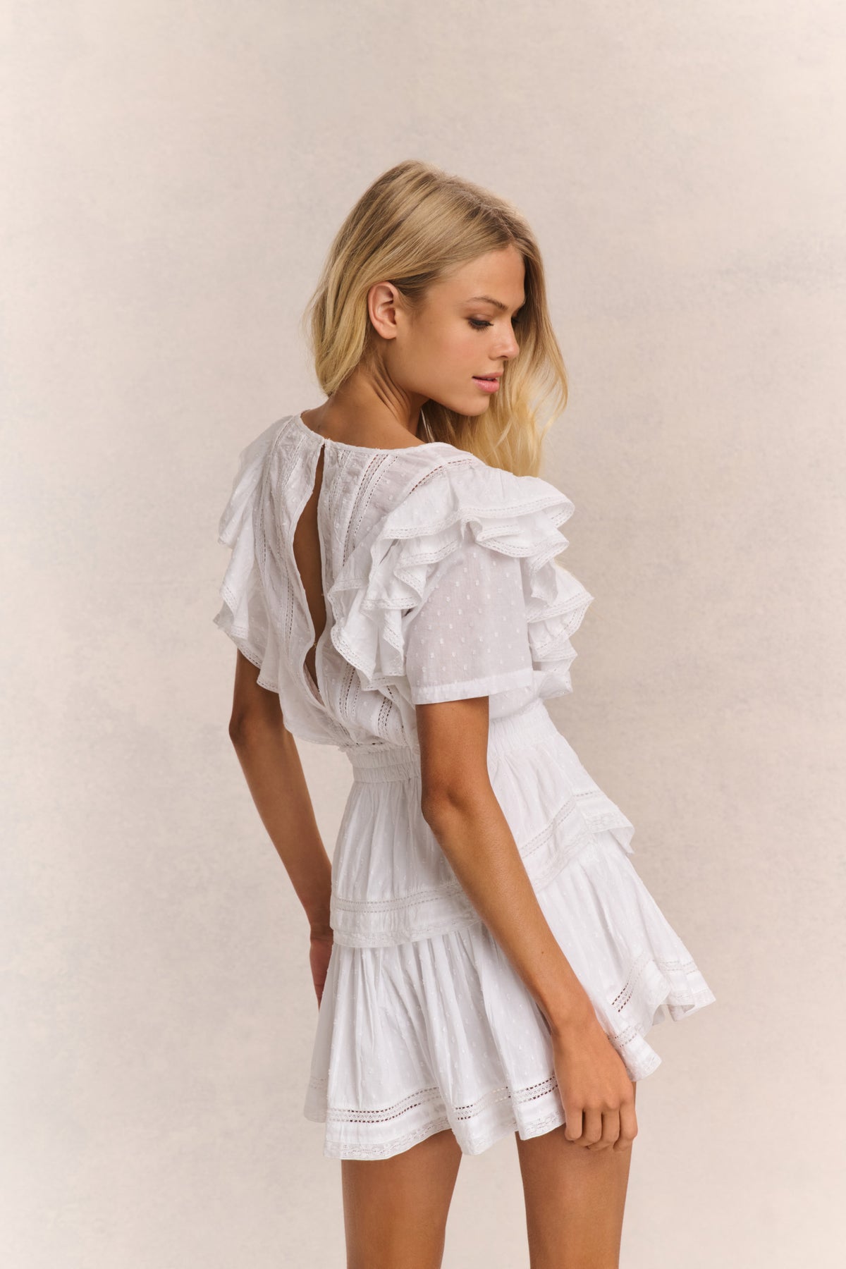 White mini dress back view with ruffle sleeves and open back cutout