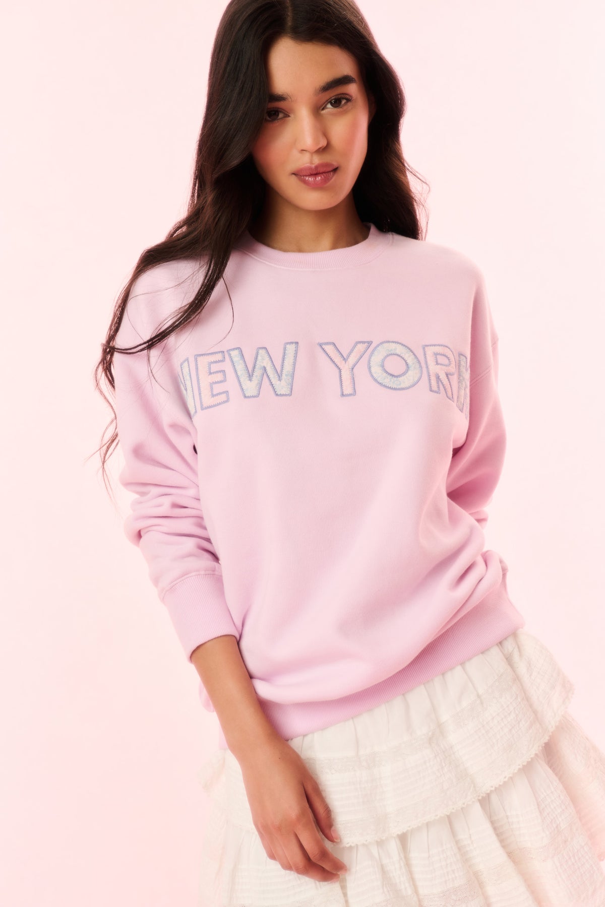 Pink pullover sweatshirt with NEW YORK graphic on chest and ribbed crew neckline