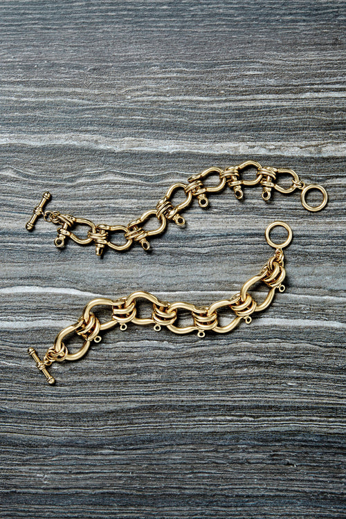 Gold link bracelet with nautical ring charms and lobster clasp, laid flat