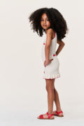 Little girls cherry knit dress with red trim, bow accents, and ruffled hem, side view