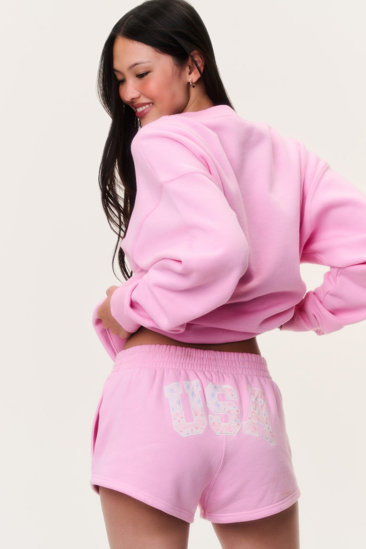 Pink fleece pullover back view with "USA" graphic patch on shorts waistband area.