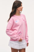 Pink tween varsity pullover sweatshirt with embroidered crest patch and long sleeves