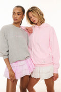 Gray and pink pullover sweatshirts paired together, both with small chest logo graphic