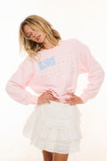 Pink fleece pullover with crew neck and multicolor stripe graphic, side view