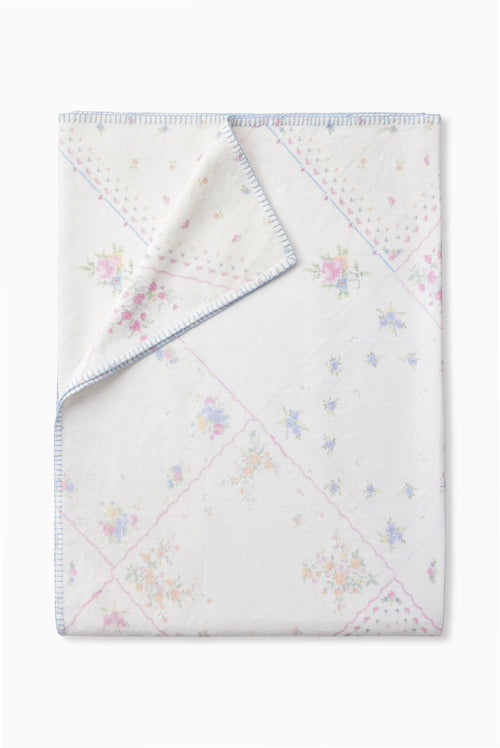 Patchwork table linen, white base with pastel flower motifs and blue stitched border.
