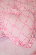 Pink heart pillow close-up with ruffled trim and bow pattern on fabric