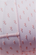 Close-up of mauve-pink bow-print fabric with stitched trim and zip placket