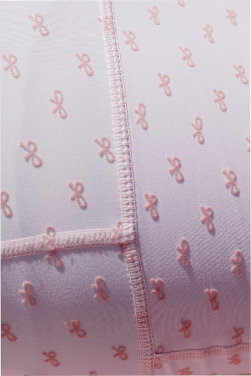 Close-up of mauve-pink bow-print fabric with stitched trim and zip placket