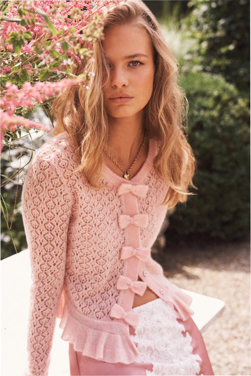 Light pink pointelle cardigan with bow-front trim and ruffle peplum hem, long sleeves