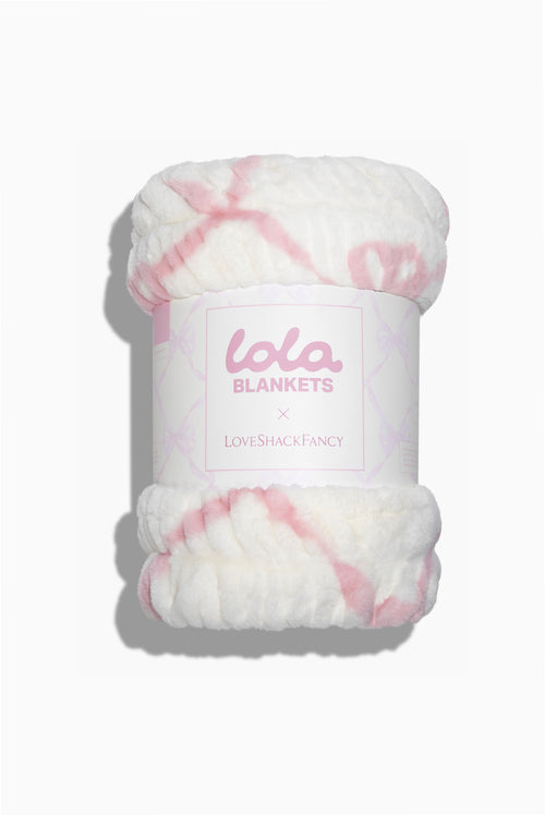 Folded blanket roll with pink bow print and brand label on front