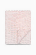 Folded throw blanket in petal pink textured with a soft, frosted finish