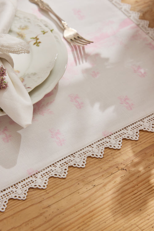 Pink place mat corner with scalloped lace border and delicate floral pattern