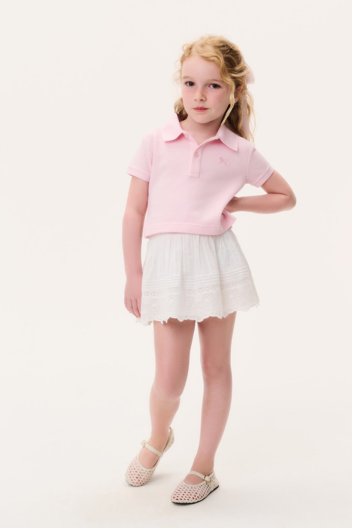 Girls' pink polo shirt with collar and short sleeves, worn with a light skirt