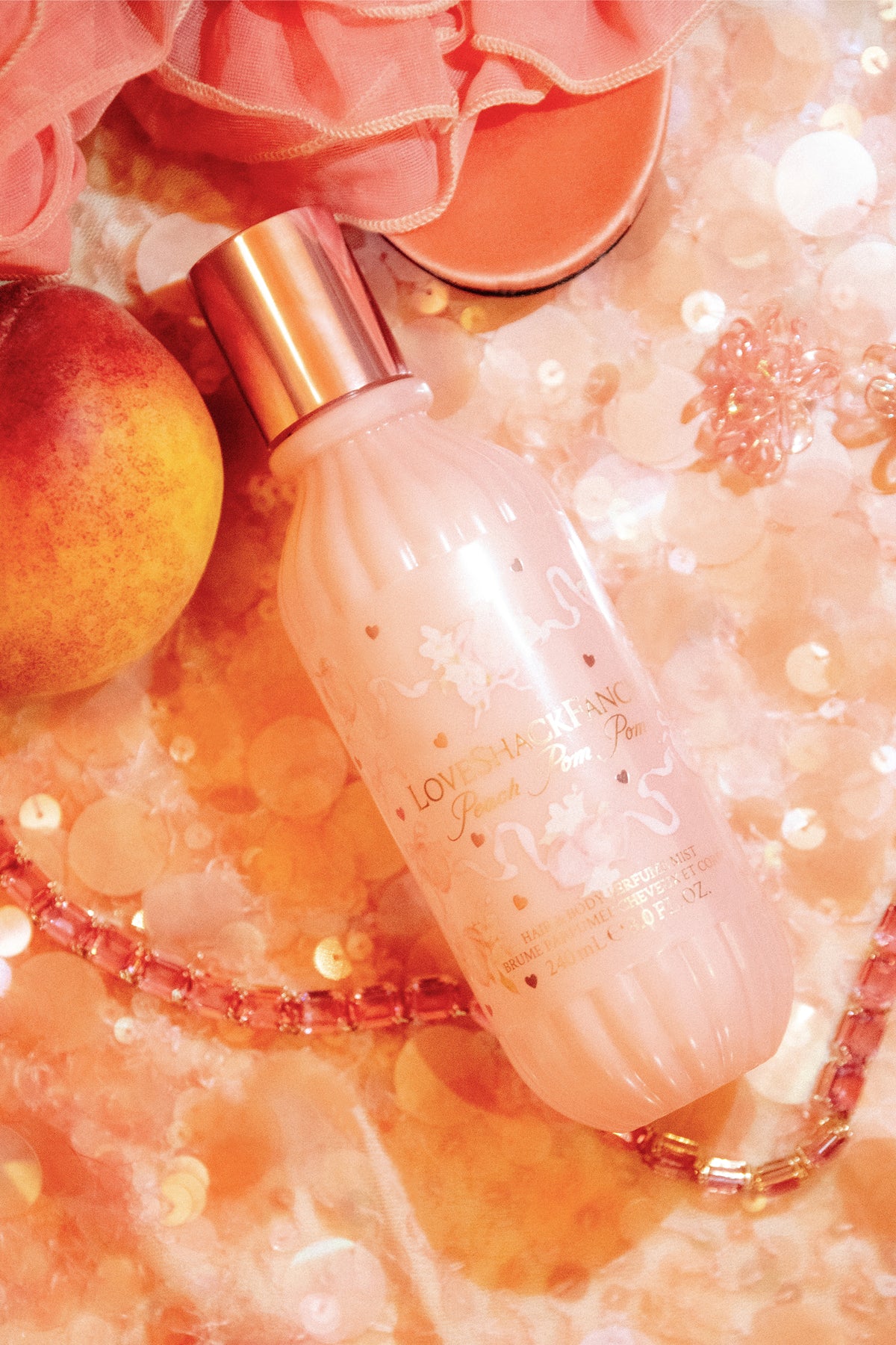 Pink hair and body perfume mist bottle with copper cap and sparkly decorative backdrop