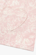 Kids pink apron detail with scalloped heart-shaped bib panel and stitched edge