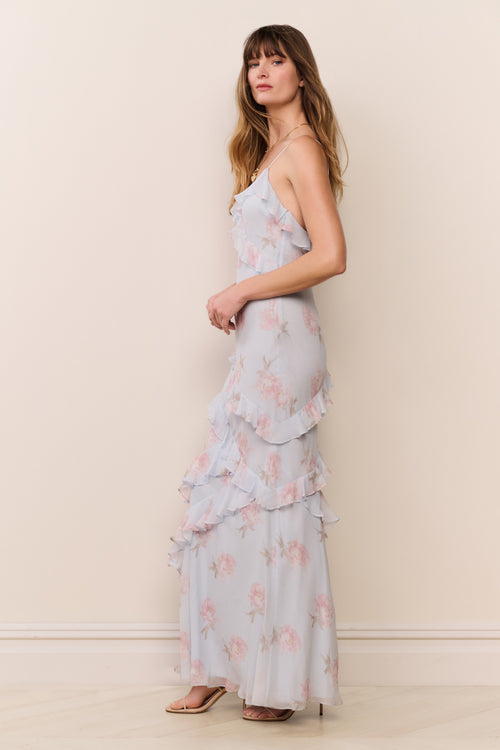 Woman wearing a light blue floral dress against a beige wall