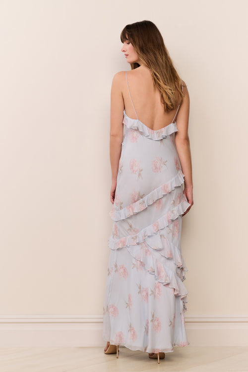 Woman wearing a light blue floral dress against a beige wall