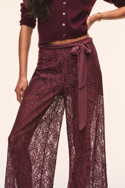 Close-up of faded merlot sheer lace wide-leg pants with bow-tied waist and floral pattern.