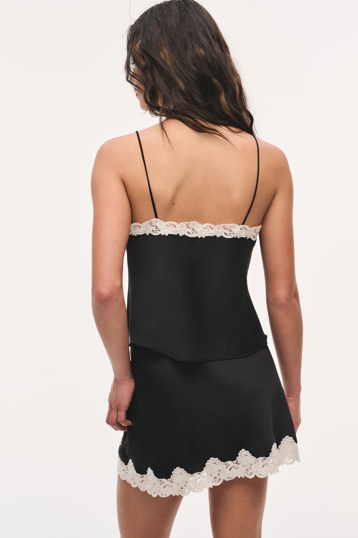 Black crepe lace cami with spaghetti straps and scalloped lace hem at back.