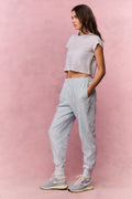Light blue printed cotton sweatpants on model, side view with elastic cuffs and tapered legs