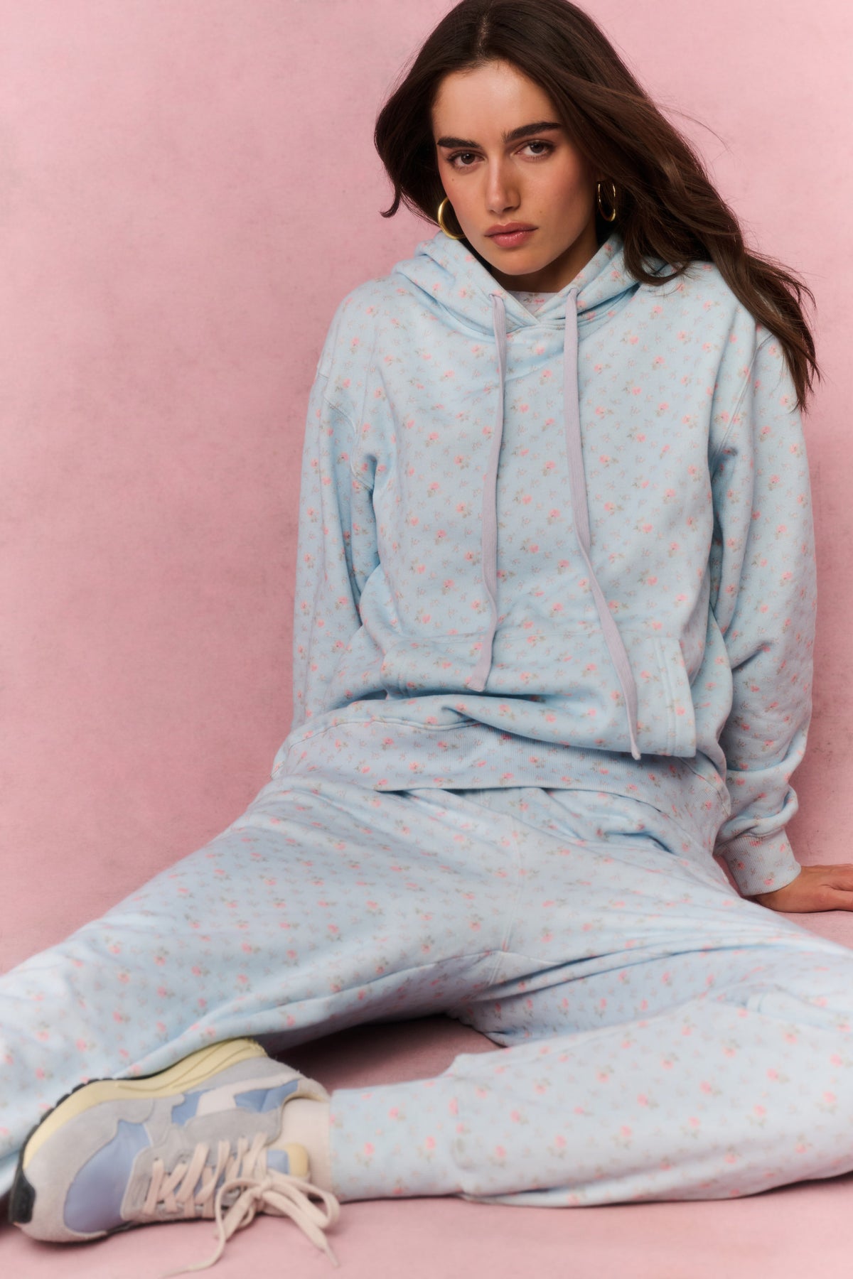 Light blue cotton pullover hoodie with hood and drawstring, front view while seated