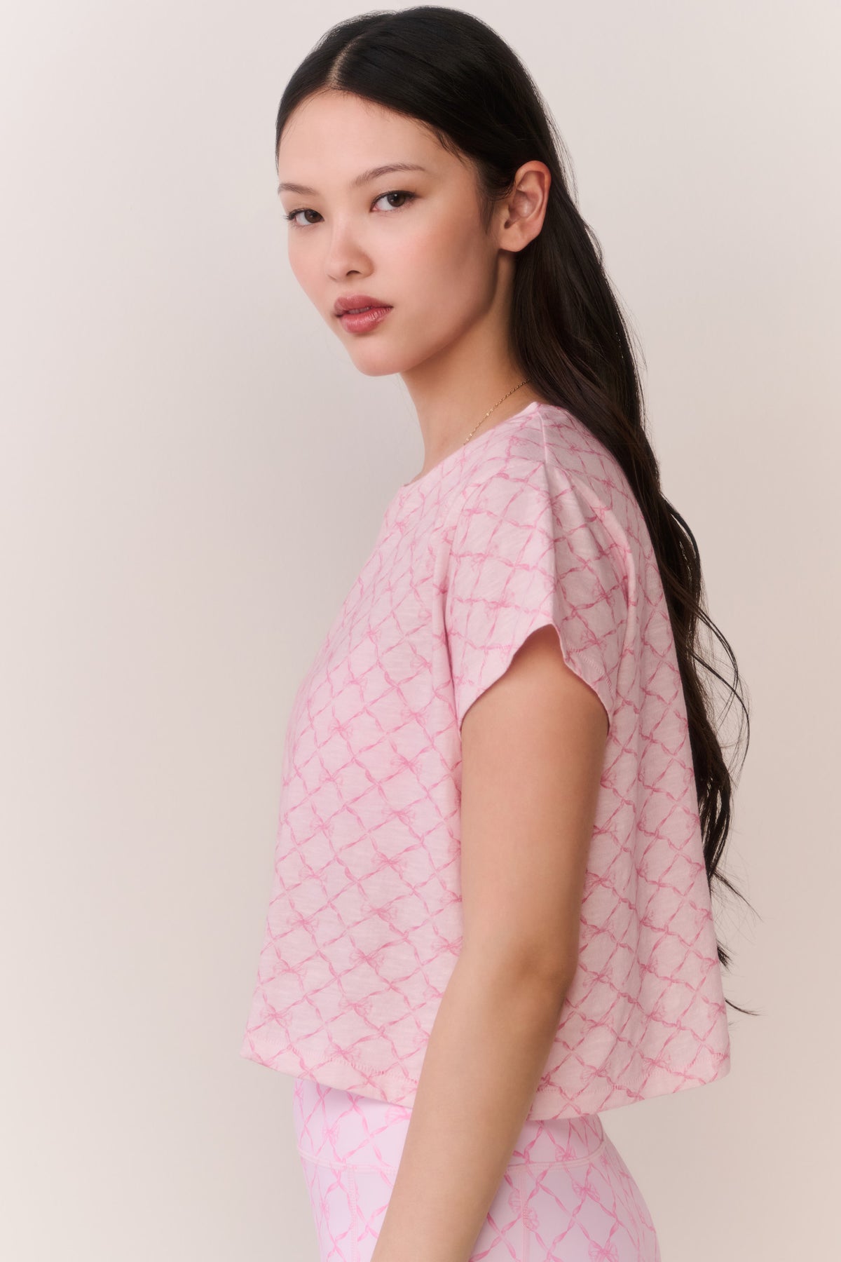 Pink cropped tee with lattice pattern, short sleeve silhouette from the side