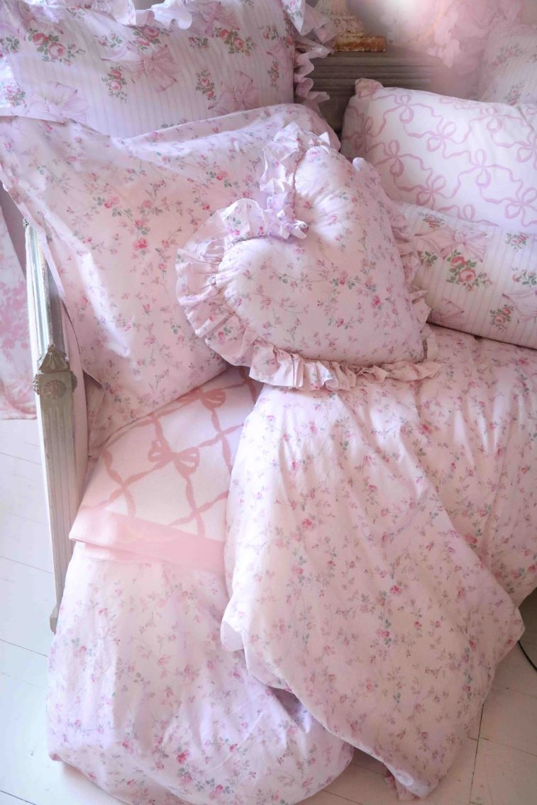Pink floral ruffle throw pillows with gathered edges on a layered bedding set