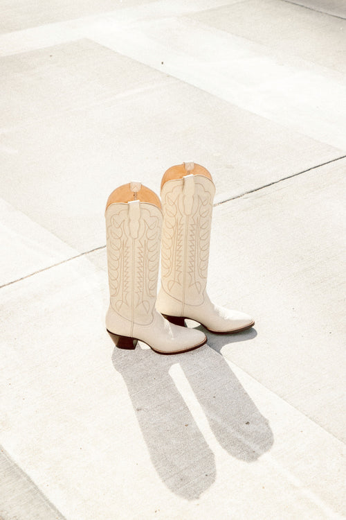 Pair of bone cowboy boots with embossed design, pointed toe, and short stacked heel