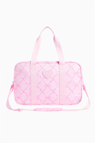 Pink quilted duffle bag with ribbon handles and heart-shaped accent panels