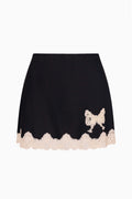 Black crepe mini skirt with scalloped white lace hem and bow applique