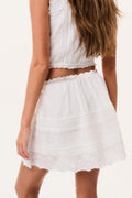 White tiered cotton mini skirt with gathered waist and scalloped lace hem