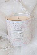 Scented candle in white glass with pink bow pattern and “Secret Crush” label, lit