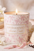 Scented candle in white jar with pink bow pattern, lit wick, “Secret Crush” label