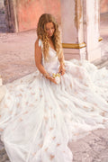 Model in a white tulle gown holding a fragrance bottle with gold ribbon