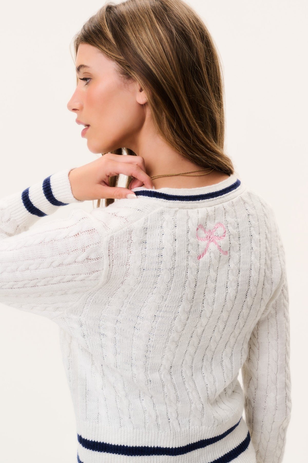 Ivory cable-knit cardigan back with navy stripe hem and pink bow embroidery