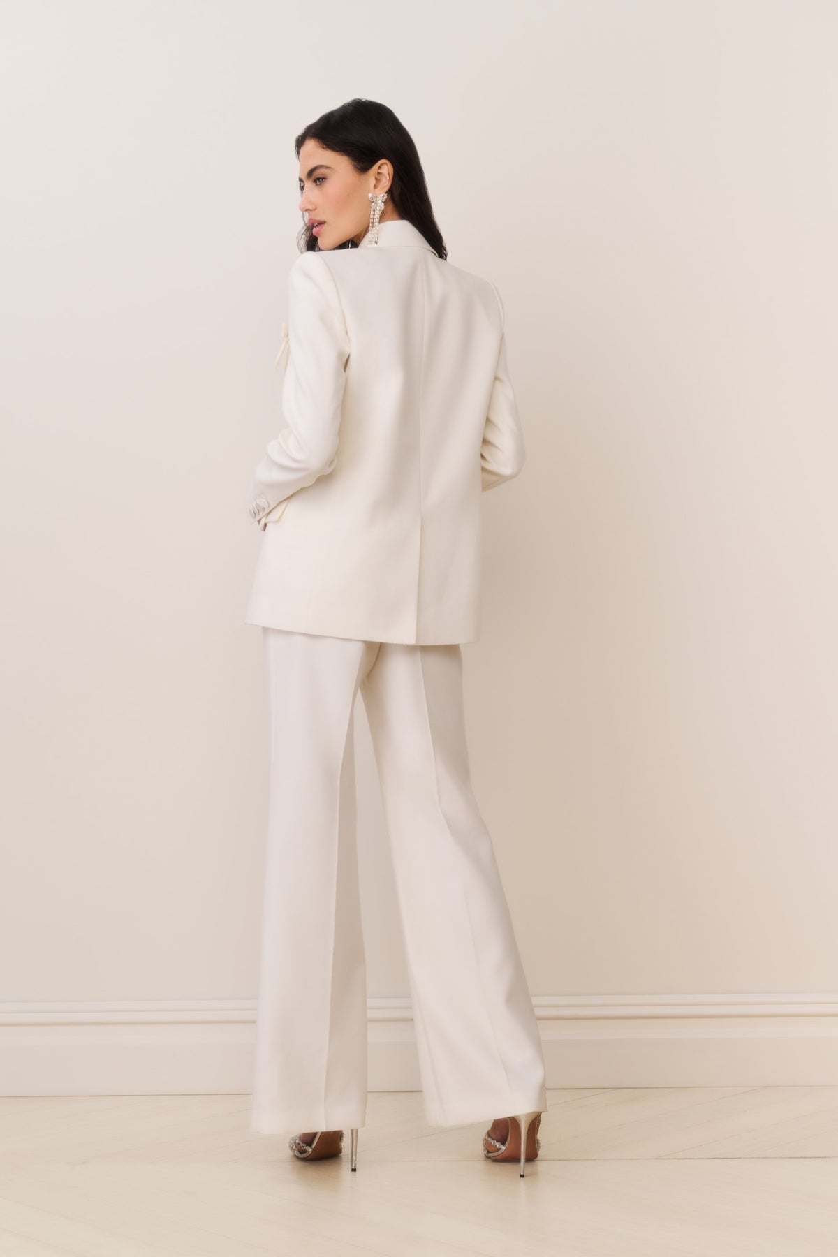 Cream wool-blend blazer with bow details on sleeve cuffs and flap pockets, back view